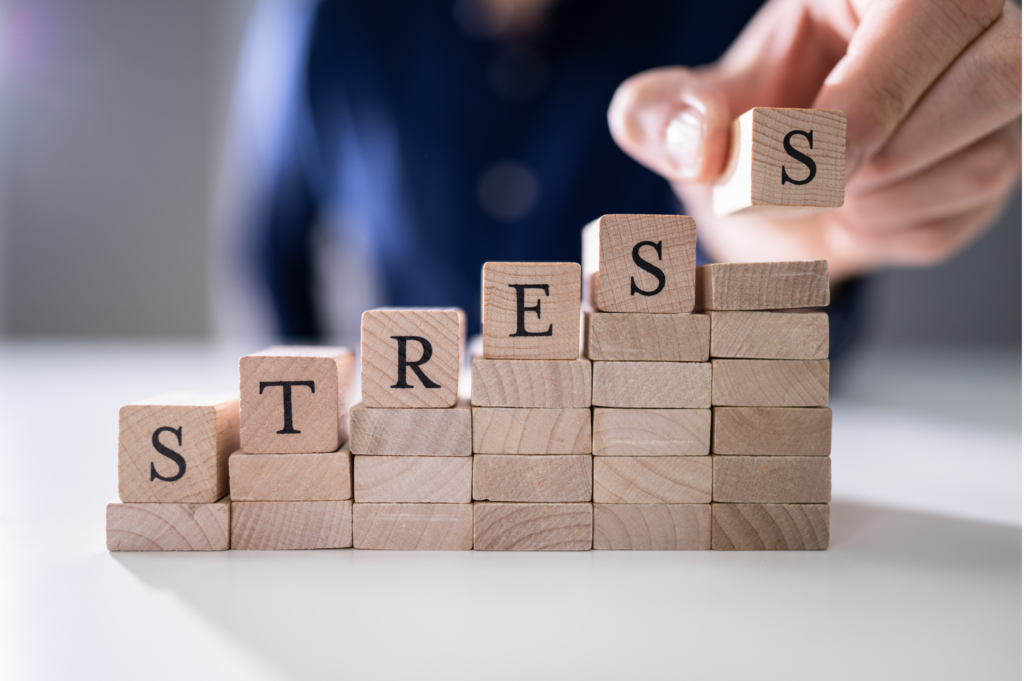 close-up of person's hand placing last alphabet of word stress on wooden block